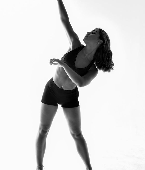 Woman in sportswear performing a gentle cardio movement in a dark studio.